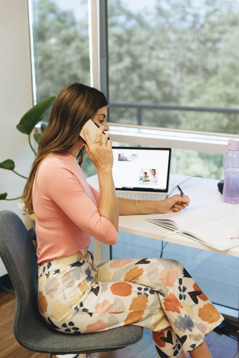 Pop Speech Therapist writing in a notebook while on the phone