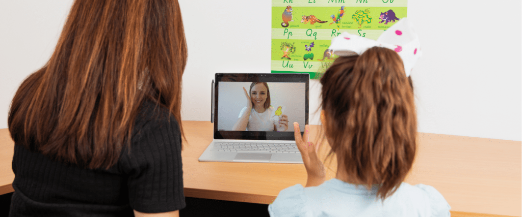 Adult and child looking at a laptop on a video call with a Pop speech therapist