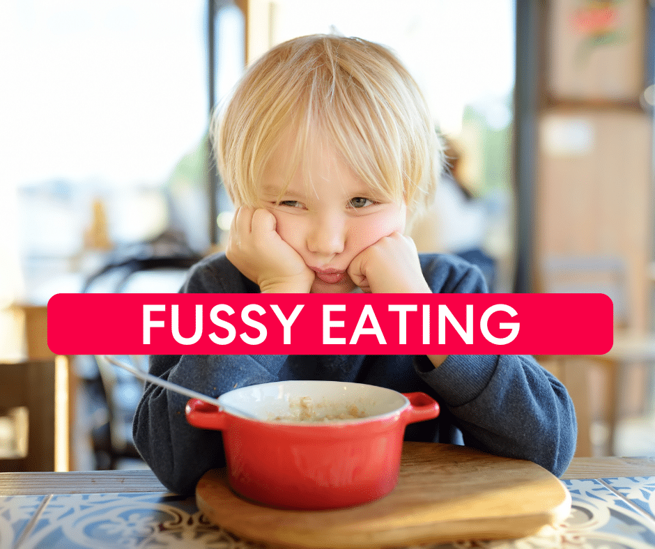 Unhappy child sitting at dining table with food and text overlayed on image saying fussy eating